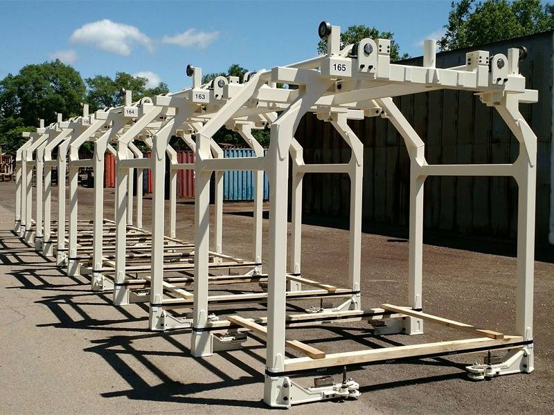 A row of painted white fabricated carrier frames standing in the yard