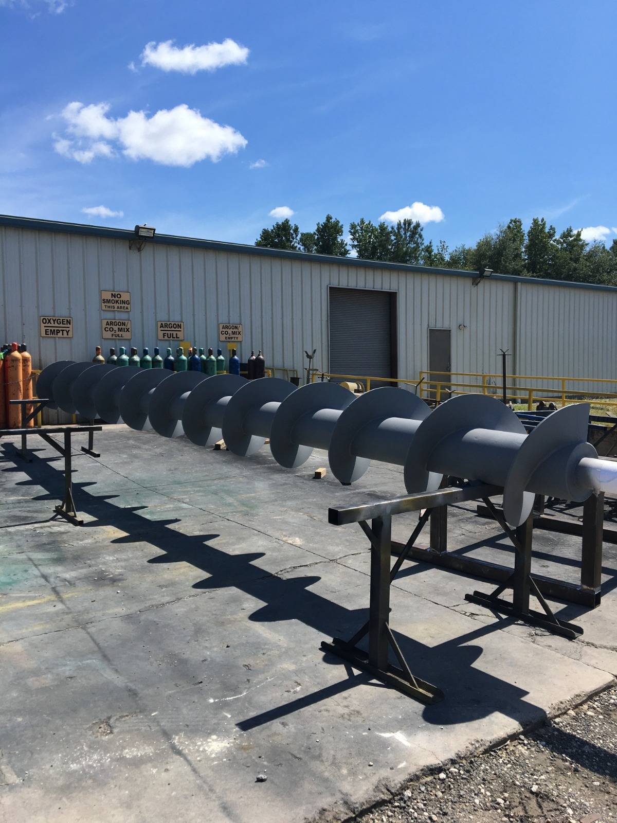 Screw conveyor supported on stands outside the plant building